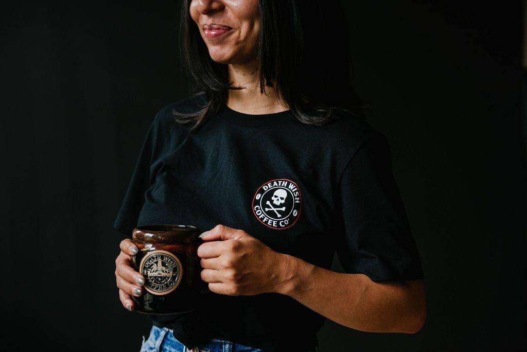 Woman holding a coffee cup wearing a Death Wish Coffee Logo T-shirt