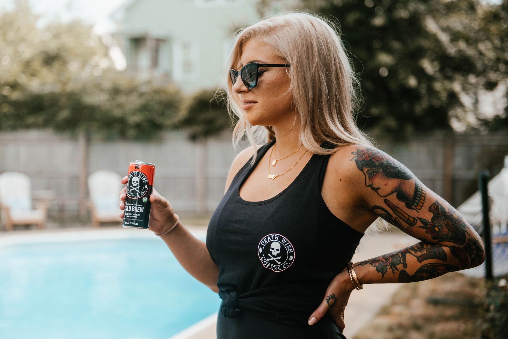 Side view of woman wearing Death Wish Coffee Logo Tank Top while drinking a Death Wish Coffee Cold Brew