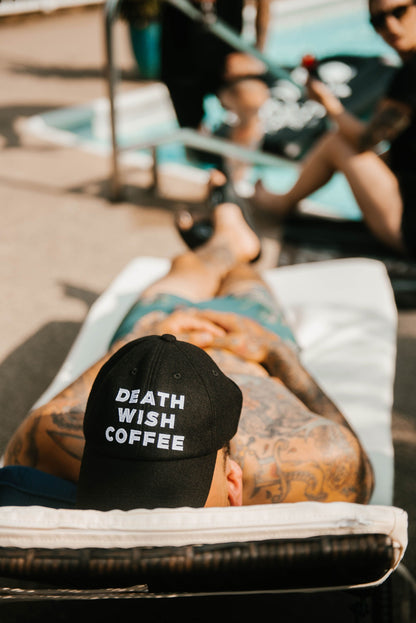 Man lying down wearing a Death Wish Coffee Baseball Hat