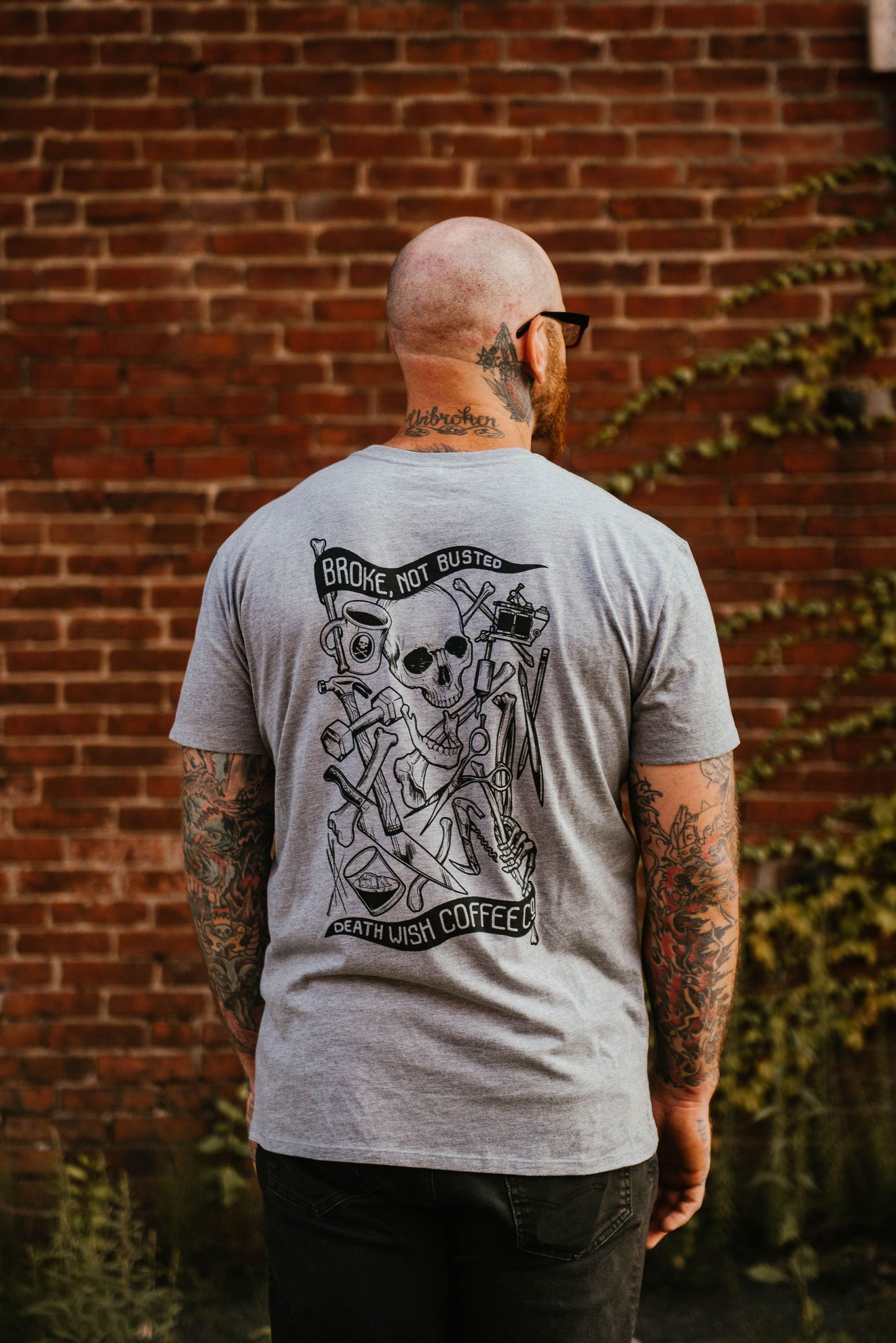 View from back of a man wearing a "Broke, Not Busted" Charity T-shirt